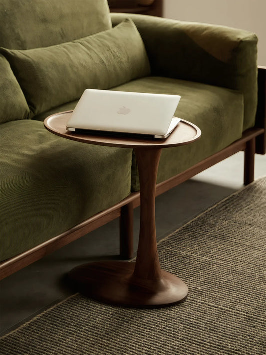 The Orbit side tables solid wood design functioning perfectly as a C-table alternative next to a velvet sofa for working on a laptop.