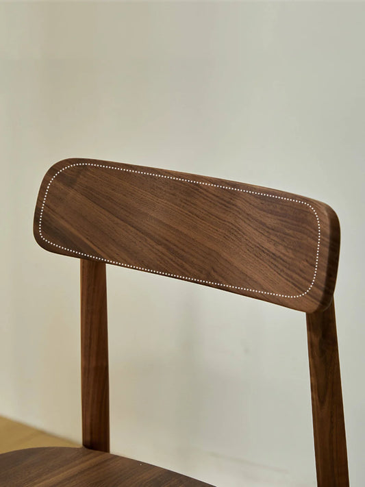 Close-up of the chair backrest from the rear, showing the broad rectangular walnut panel, rounded edges, and flowing natural grain.