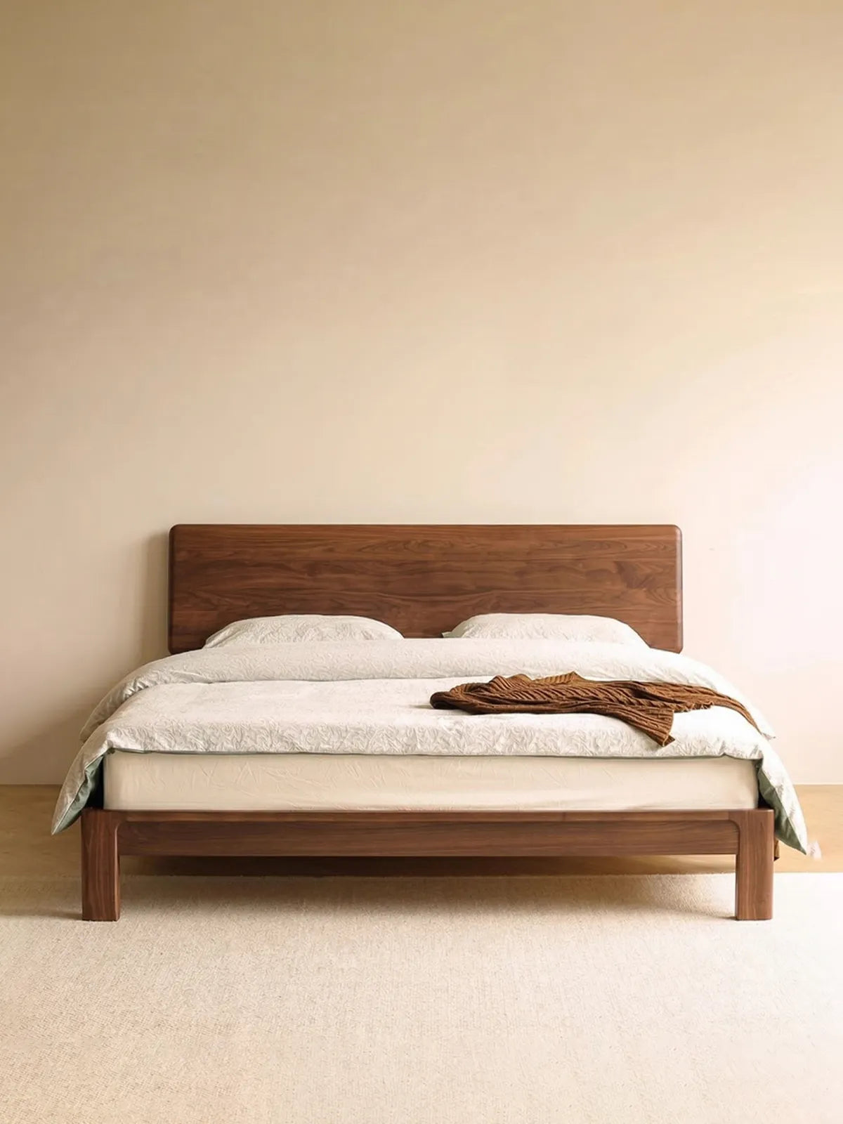 The Haven solid wood queen bed frame cleanly styled with neutral bedding against a minimalist beige wall, highlighting its timeless wooden architecture.