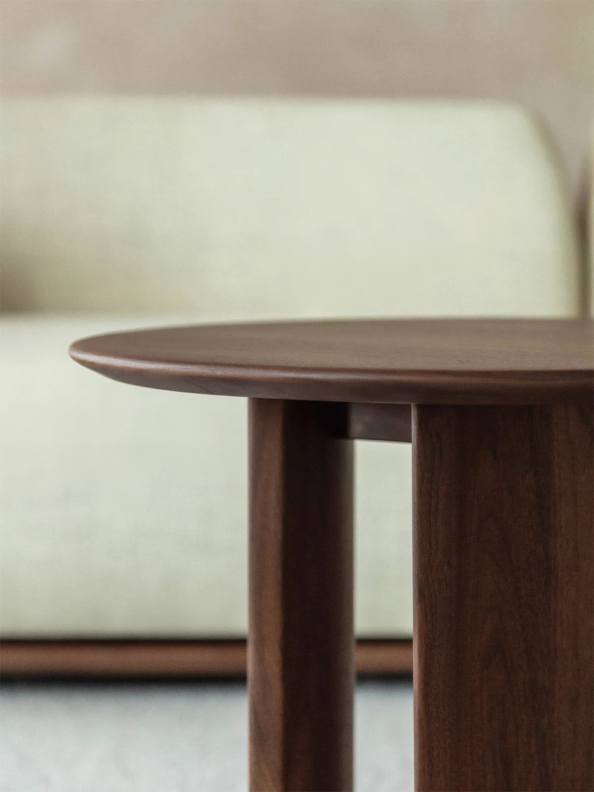 Side profile of the solid wooden side table, highlighting the robust, architectural leg design and thick tabletop edge.