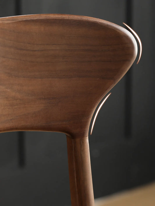 Close-up detail of the Sora chair sculpted walnut backrest with cutaway joinery and visible wood grain