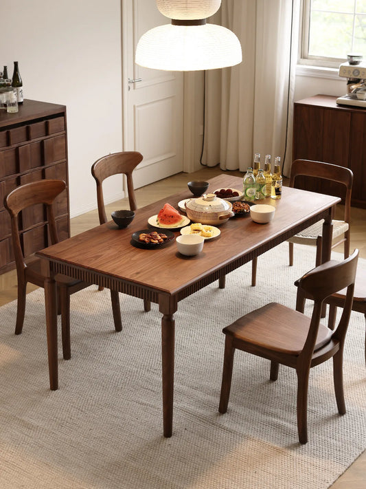 Four Sora walnut dining chairs around a set dining table in a warm, naturally lit dining room
