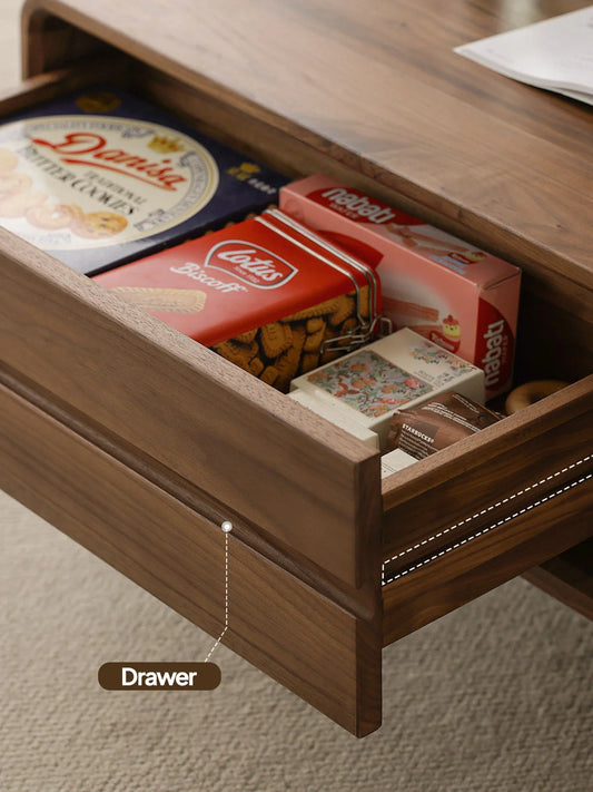 Open drawer detail of a walnut coffee table with built-in storage and recessed pull design