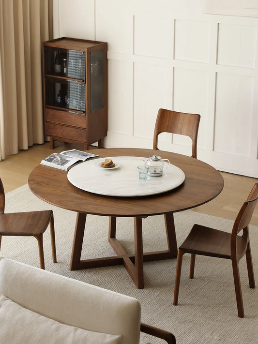 Overhead room view of a round walnut dining table with marble lazy Susan, walnut chairs, and minimalist dining room styling.