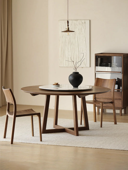 Round walnut dining table with white marble lazy Susan beneath a pendant light, shown with two walnut chairs and a glass-front cabinet.