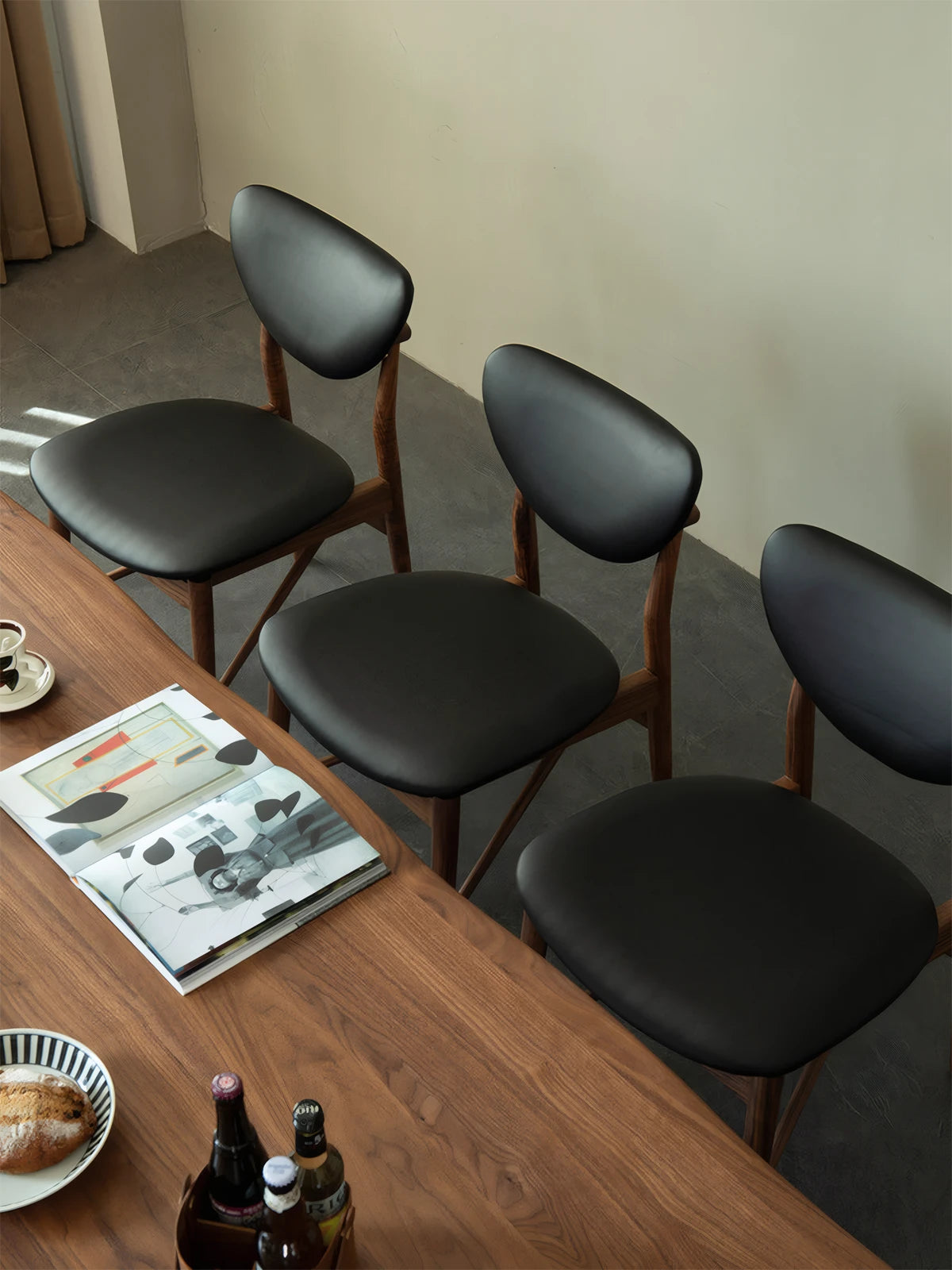 Overhead view of the contoured black leather seat cushion on the Sylvan black and walnut dining chairs, highlighting the sleek minimalist design.