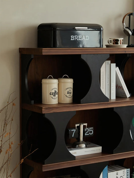 Sylvan geometric walnut shelf used as a mid century modern divider in a living room, styled with vintage accessories and plants.