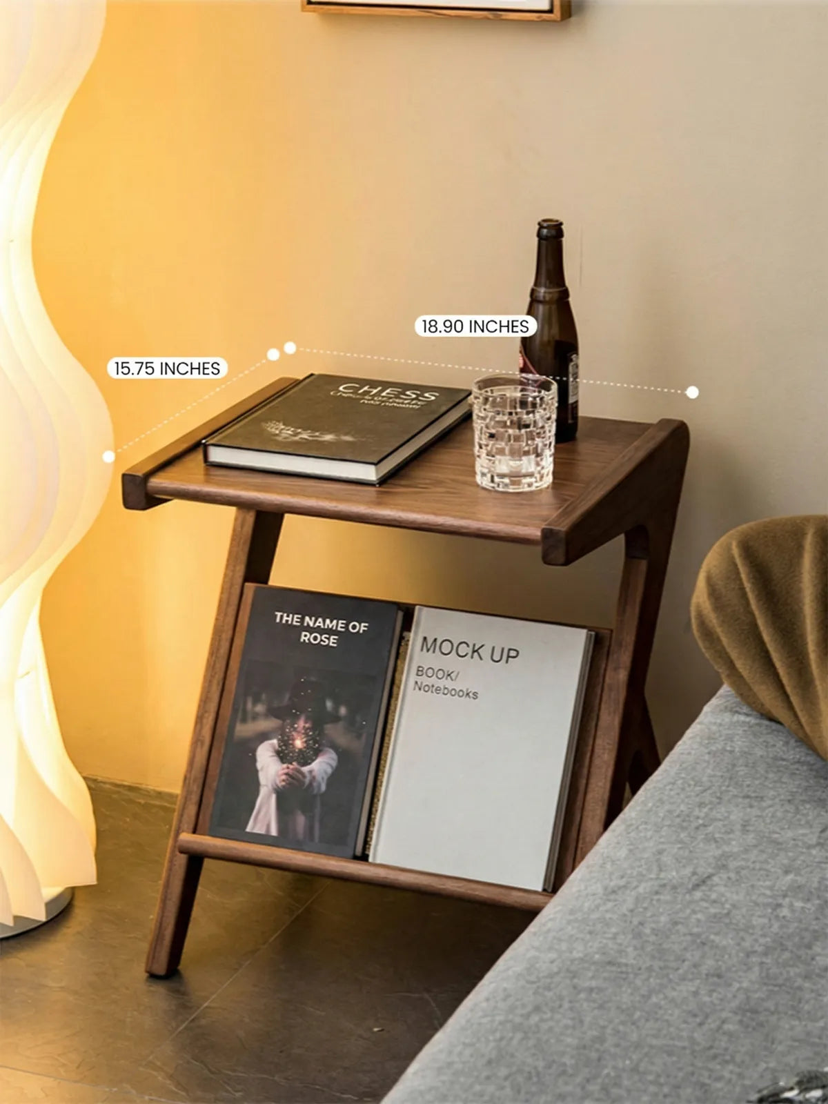Sylvan walnut side table styled with books and whiskey glass, highlighting the V-shaped cane magazine rack storage.