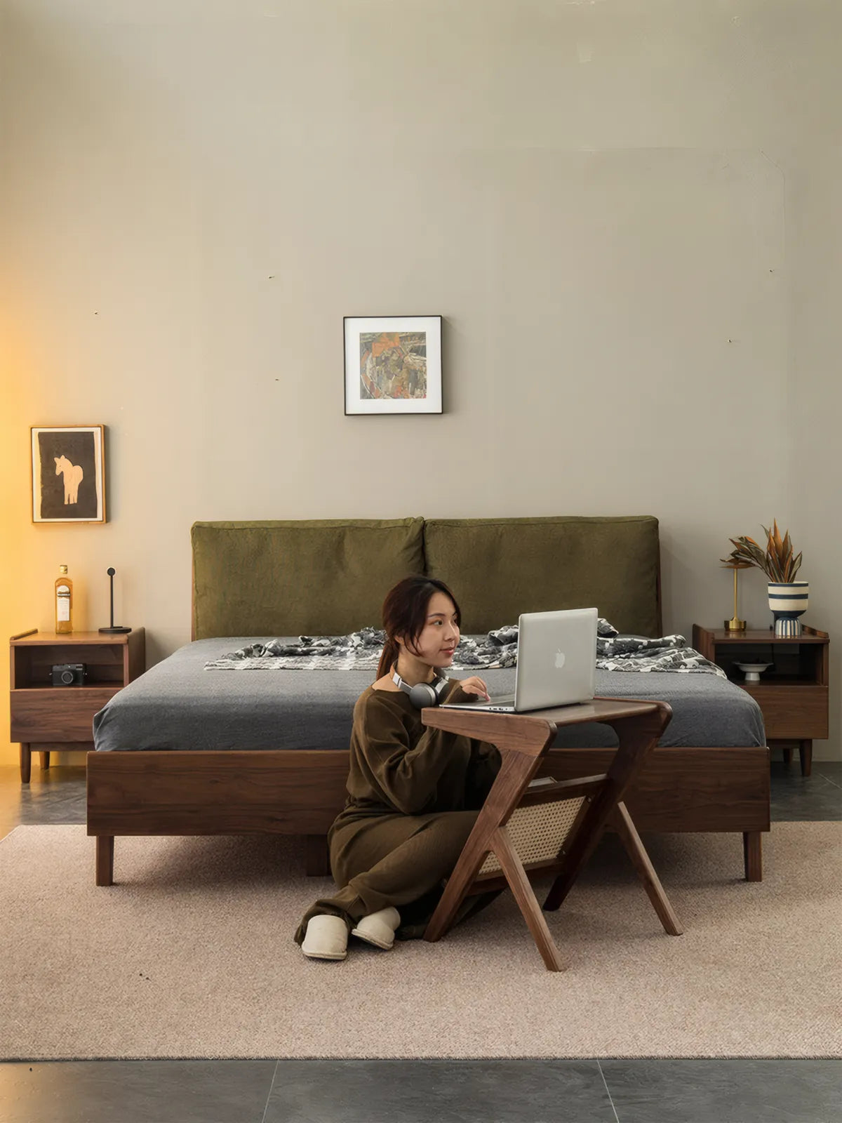 Woman sitting on floor using Sylvan solid walnut Z-table as a laptop desk, showcasing ergonomic height and cantilever design.