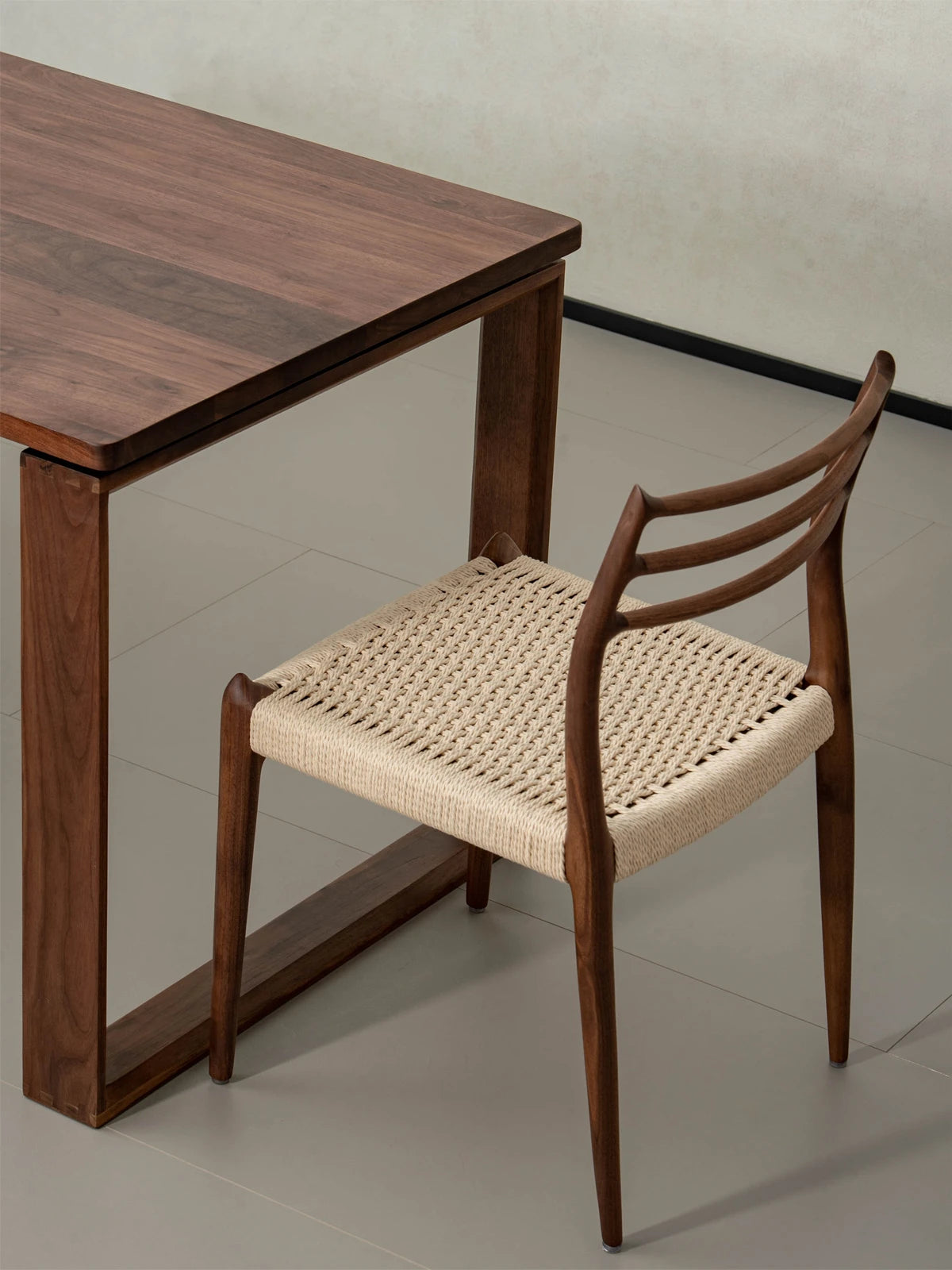 Angled top-down view of The Haven Dining Chair with a woven paper cord seat, beautifully paired with a matching solid Black Walnut dining table.