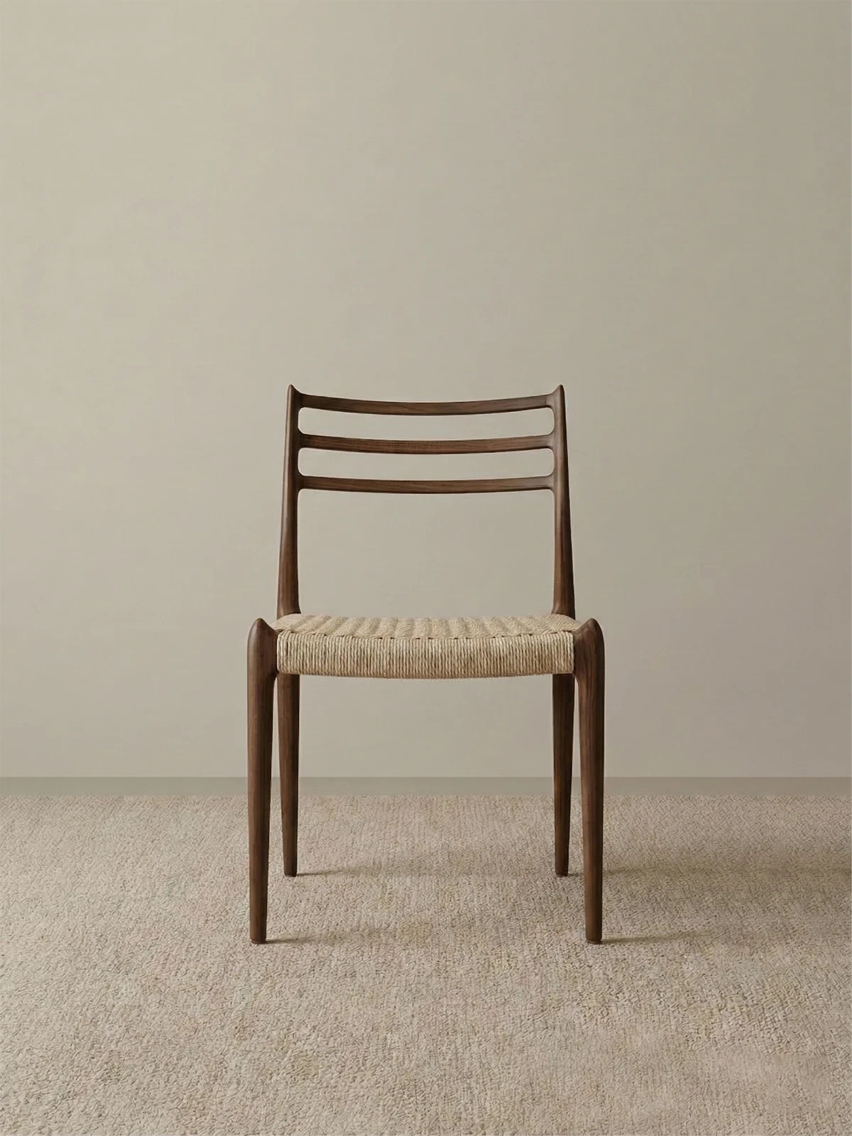 Front studio view of The Haven Dining Chair displaying its mid-century modern design, textured woven seat, and sturdy solid Black Walnut legs against a neutral background.