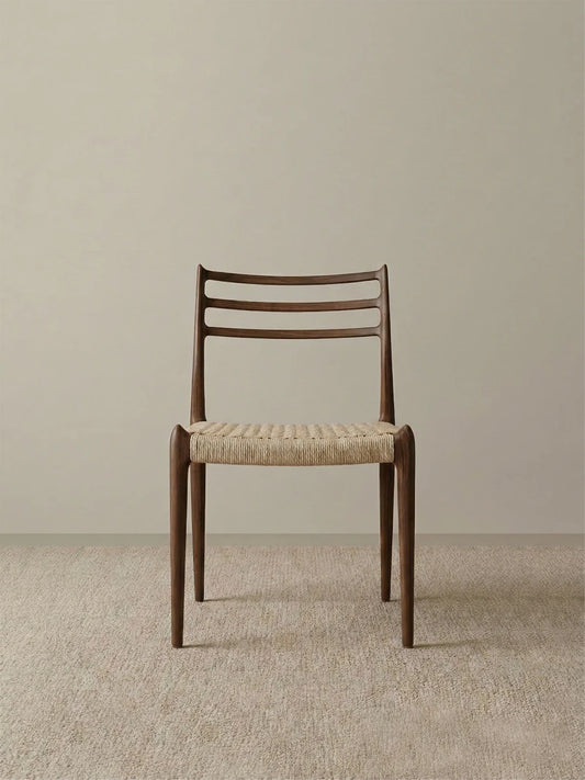 Front studio view of The Haven Dining Chair displaying its mid-century modern design, textured woven seat, and sturdy solid Black Walnut legs against a neutral background.