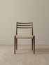Front studio view of The Haven Dining Chair displaying its mid-century modern design, textured woven seat, and sturdy solid Black Walnut legs against a neutral background.