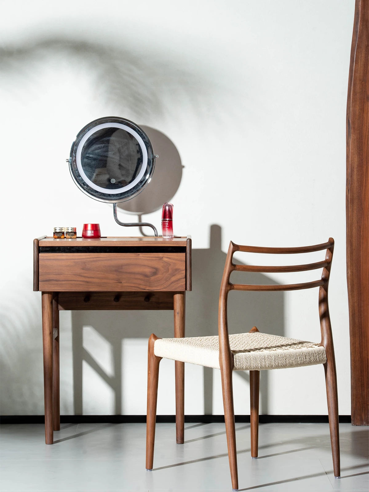 The Haven Dining Chair used as an elegant seating option at a solid Black Walnut makeup vanity desk in a bright, modern room setting.