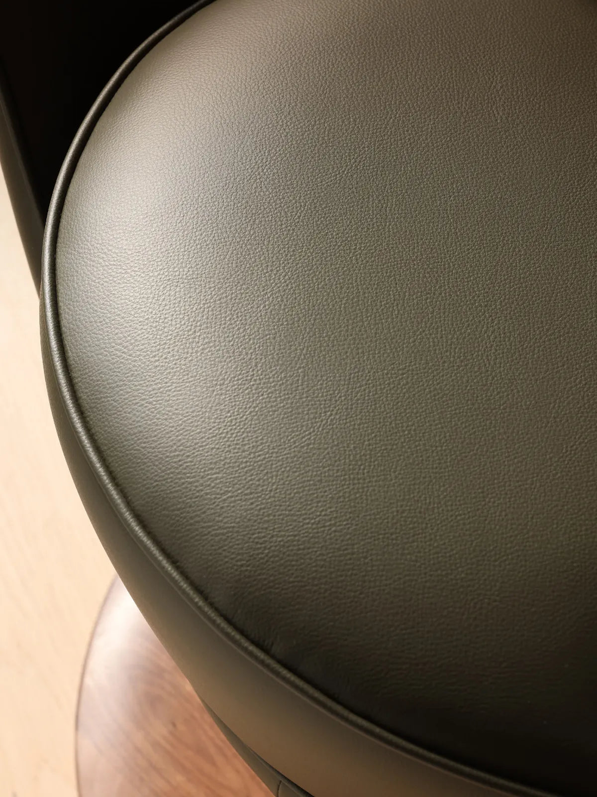 Close-up view of the smooth, high-quality green leather seat cushion on The Helios Retreat Swivel Recliner.
