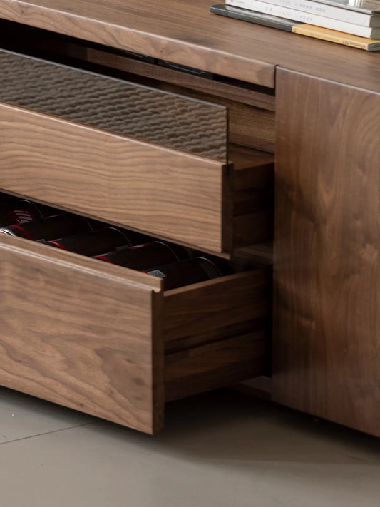 Partially open solid wood drawers of The Pebble Media Console revealing ample storage space, situated below a textured fluted glass drop-down door.