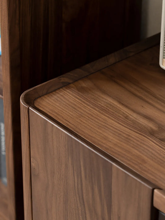 Macro close-up of The Pebble Media Console, showcasing the finely crafted raised edge lip and beautiful natural walnut wood grain.