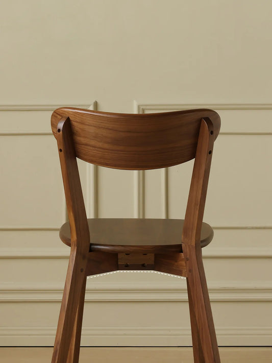 Detailed back view of The Sylva Dining Chair, showcasing the premium craftsmanship and natural grain patterns of the solid Black Walnut wood.
