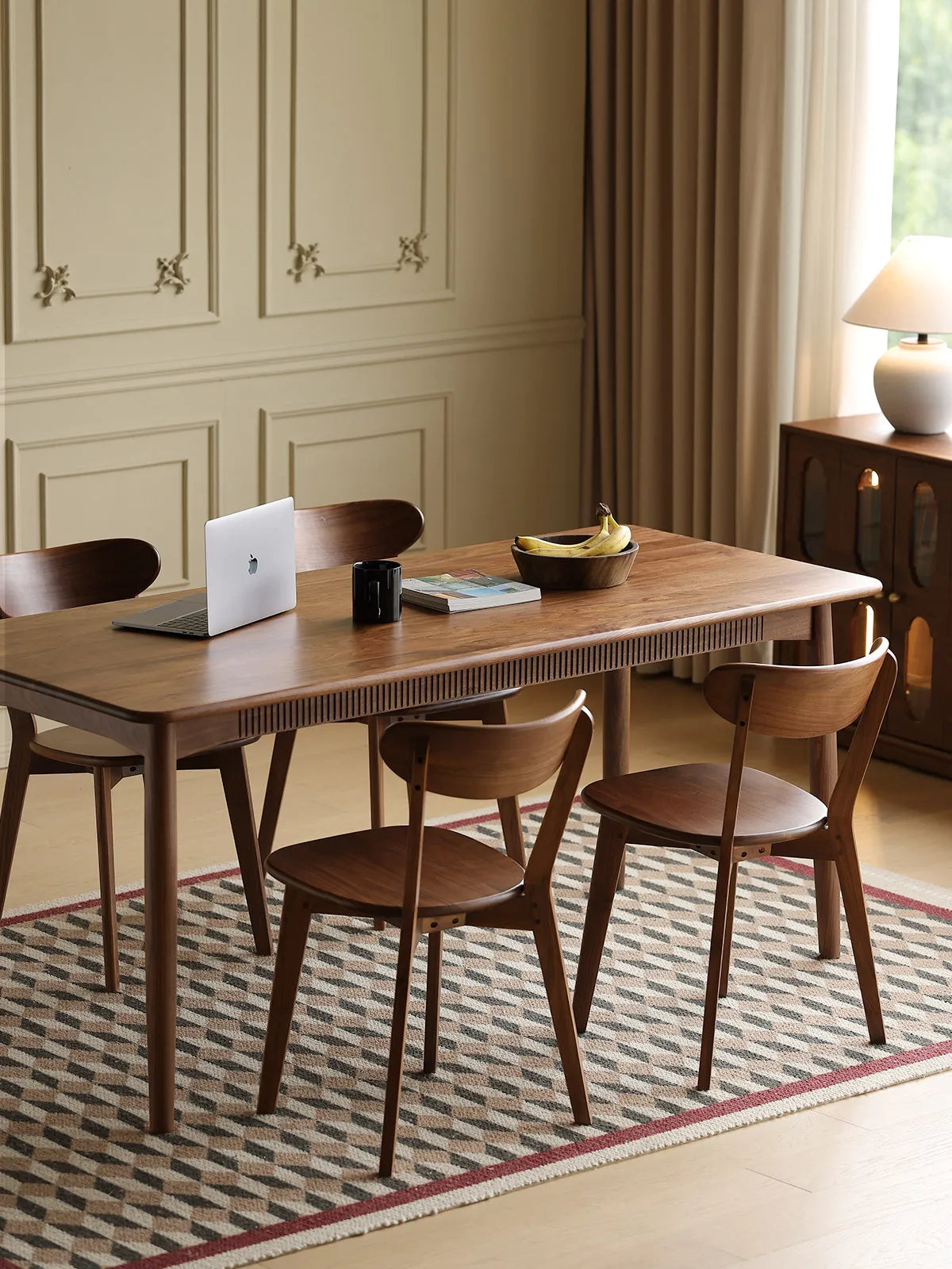 A set of four The Sylva Dining Chairs arranged neatly around a matching solid Black Walnut dining table in a bright, contemporary home workspace setting.