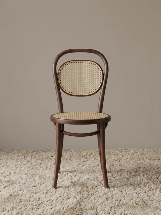 Tovin bentwood dining chair in solid walnut with handwoven cane seat and oval cane backrest, front view on textured rug
