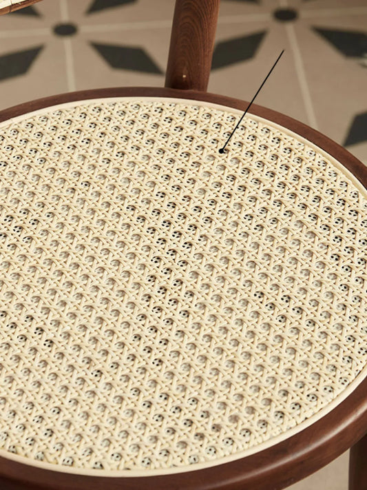 Overhead close-up of the round handwoven rattan cane seat on the Tovin walnut dining chair