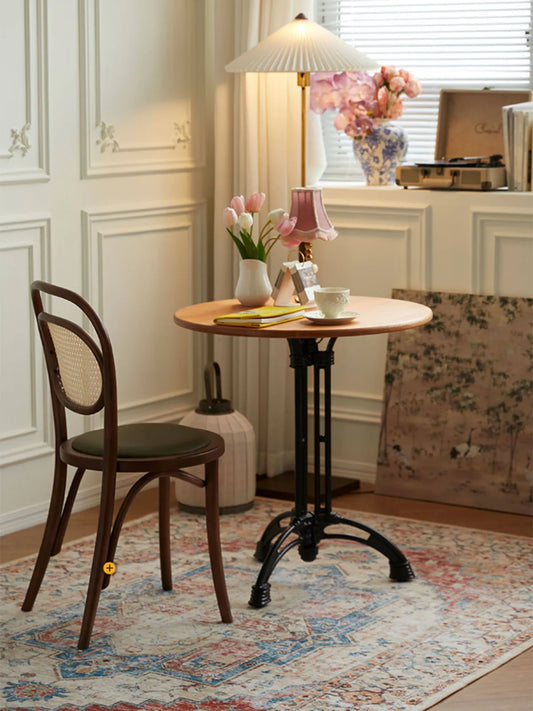 Tovin walnut bentwood dining chair with cane backrest at a round table in a bright room with wainscoting