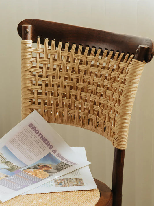 Detail of the open cross-hatch rattan weave backrest on the Vilen walnut dining chair