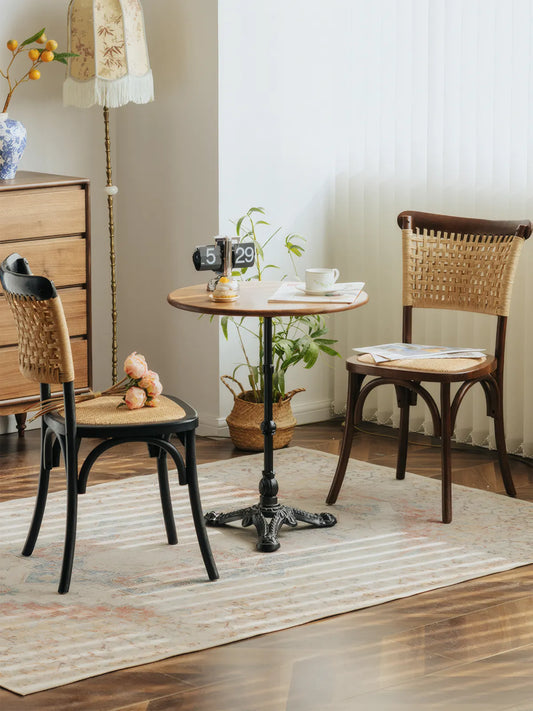 Two Vilen dining chairs — one walnut, one black — around a round bistro table in a styled room