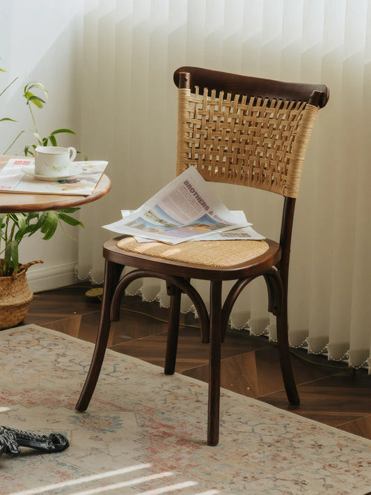 Vilen walnut dining chair at three-quarter angle beside a café table with newspaper on the seat