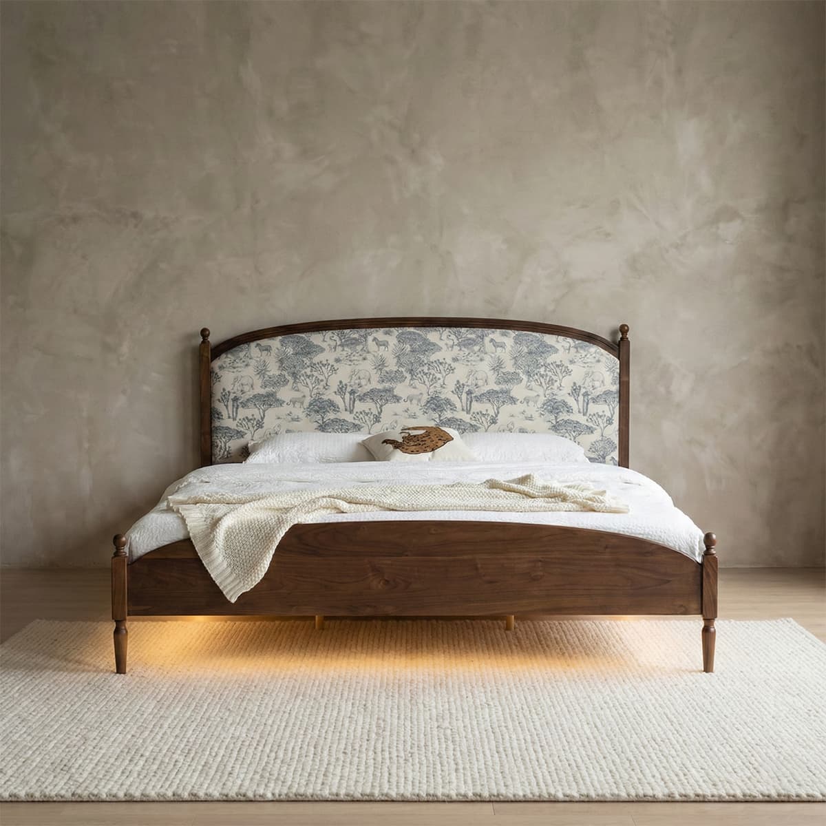 Elegant solid walnut bed frame featuring a fabric-upholstered headboard with a blue and white vintage landscape pattern and turned wooden legs.