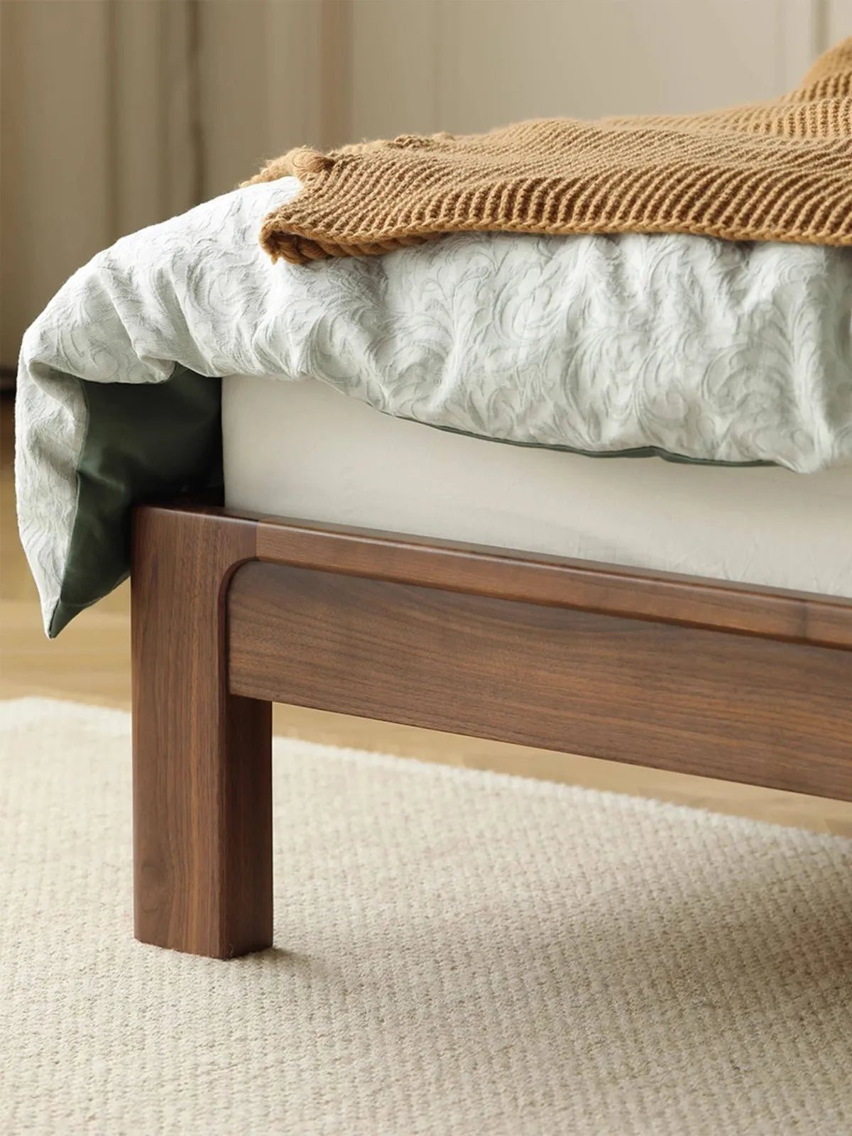 Close-up of the robust, solid front leg on the walnut bed, emphasizing its seamless, rounded construction and durable design.