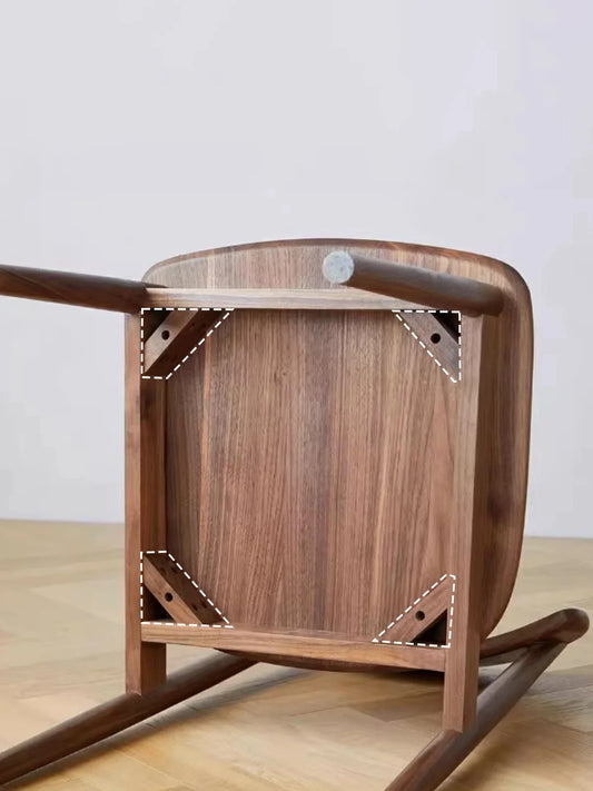 Underside view of a walnut dining chair showing the solid wood seat panel, apron frame, and reinforced corner bracing construction.