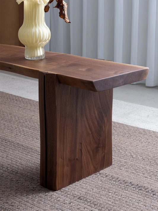 der handcrafted walnut bench close-up showing the thick slab-style leg, rich walnut grain, and sturdy solid wood construction.