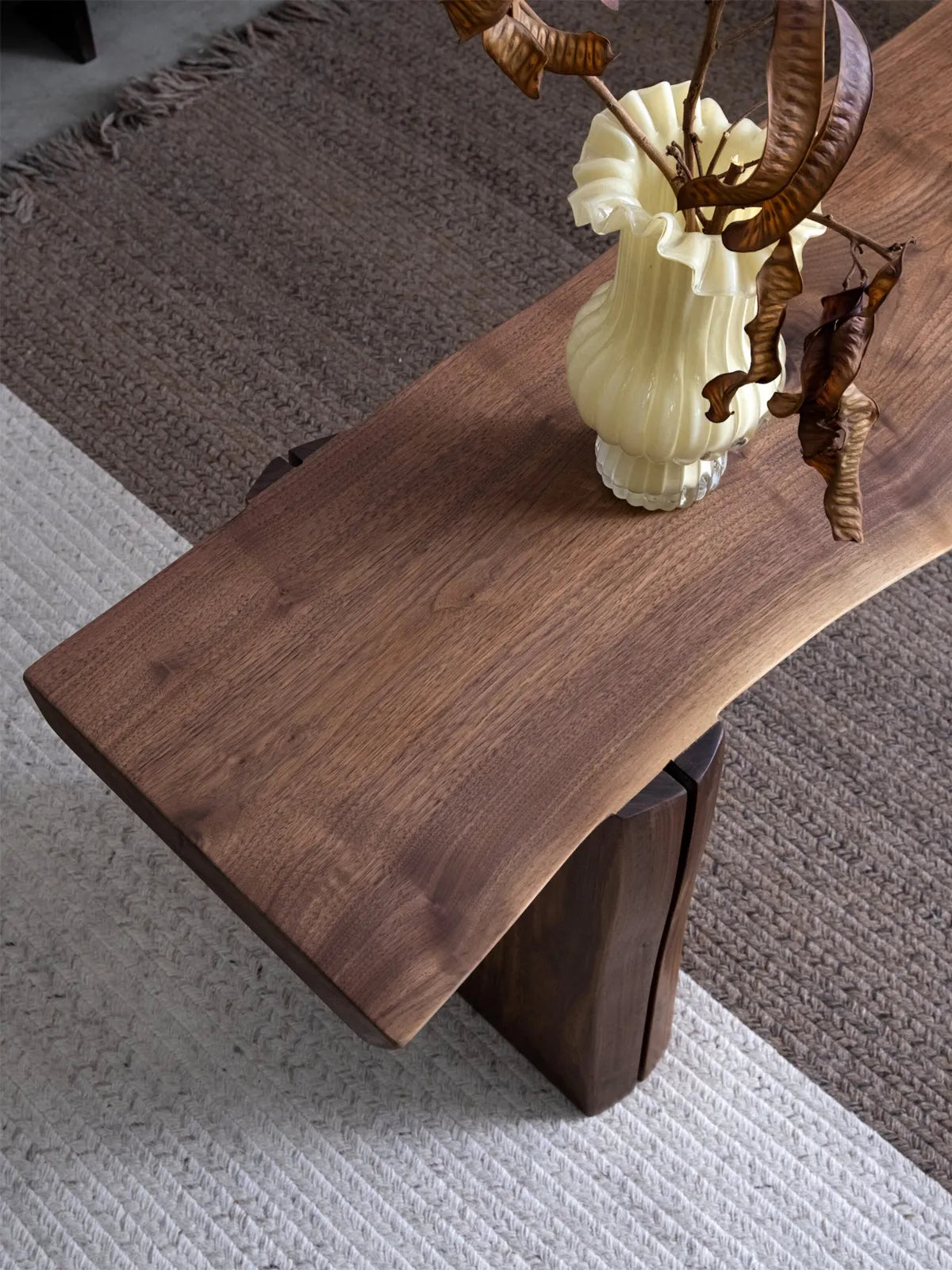 Walnutry Wilder live edge walnut bench front view, showing the balanced slab-leg construction and warm natural finish in a neutral interior.