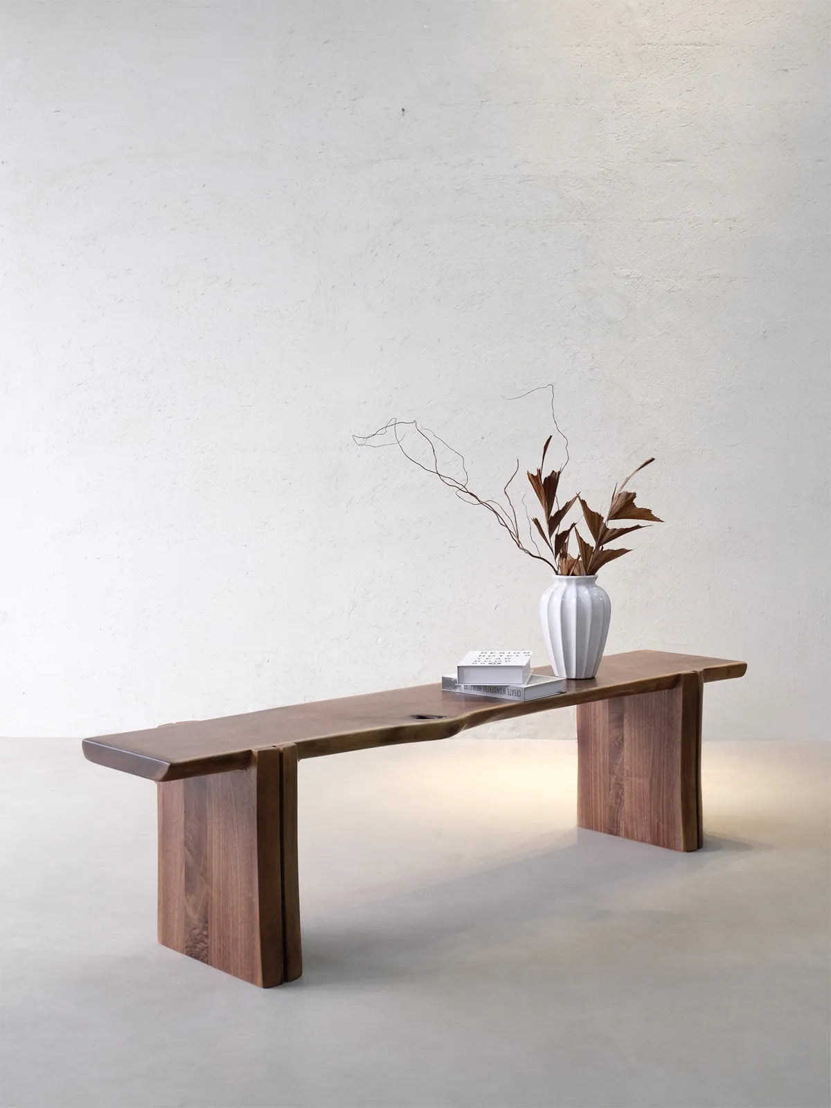 Walnutry Wilder natural edge bench full product view with a clean sculptural silhouette, organic wood seat line, and grounded slab supports.