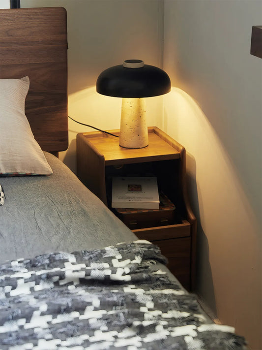 Atmospheric shot of walnut nightstand illuminated by a bedside lamp, showcasing the wood's chatoyancy.