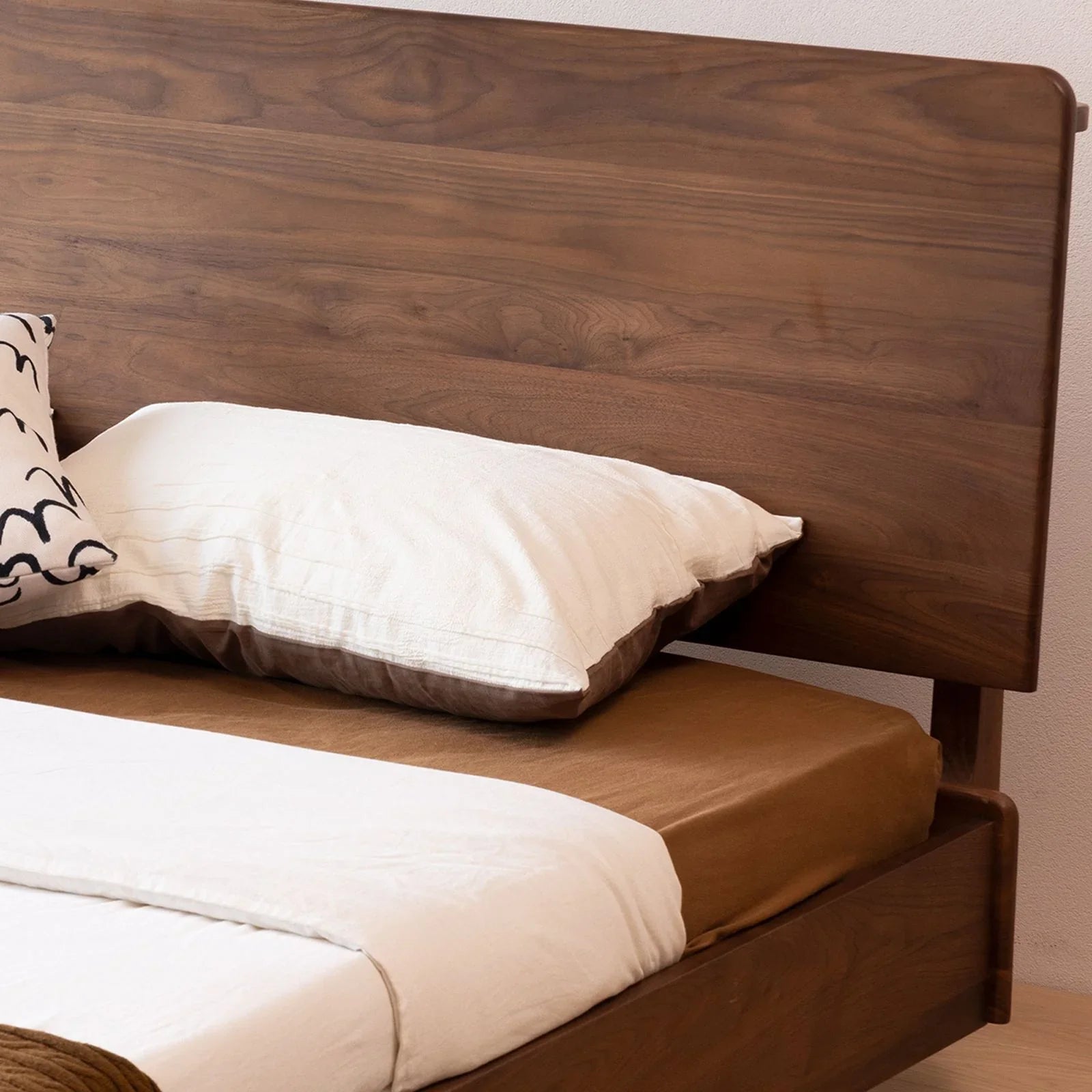 Close-up of the wide plank FAS walnut headboard showing rich natural wood grain patterns.