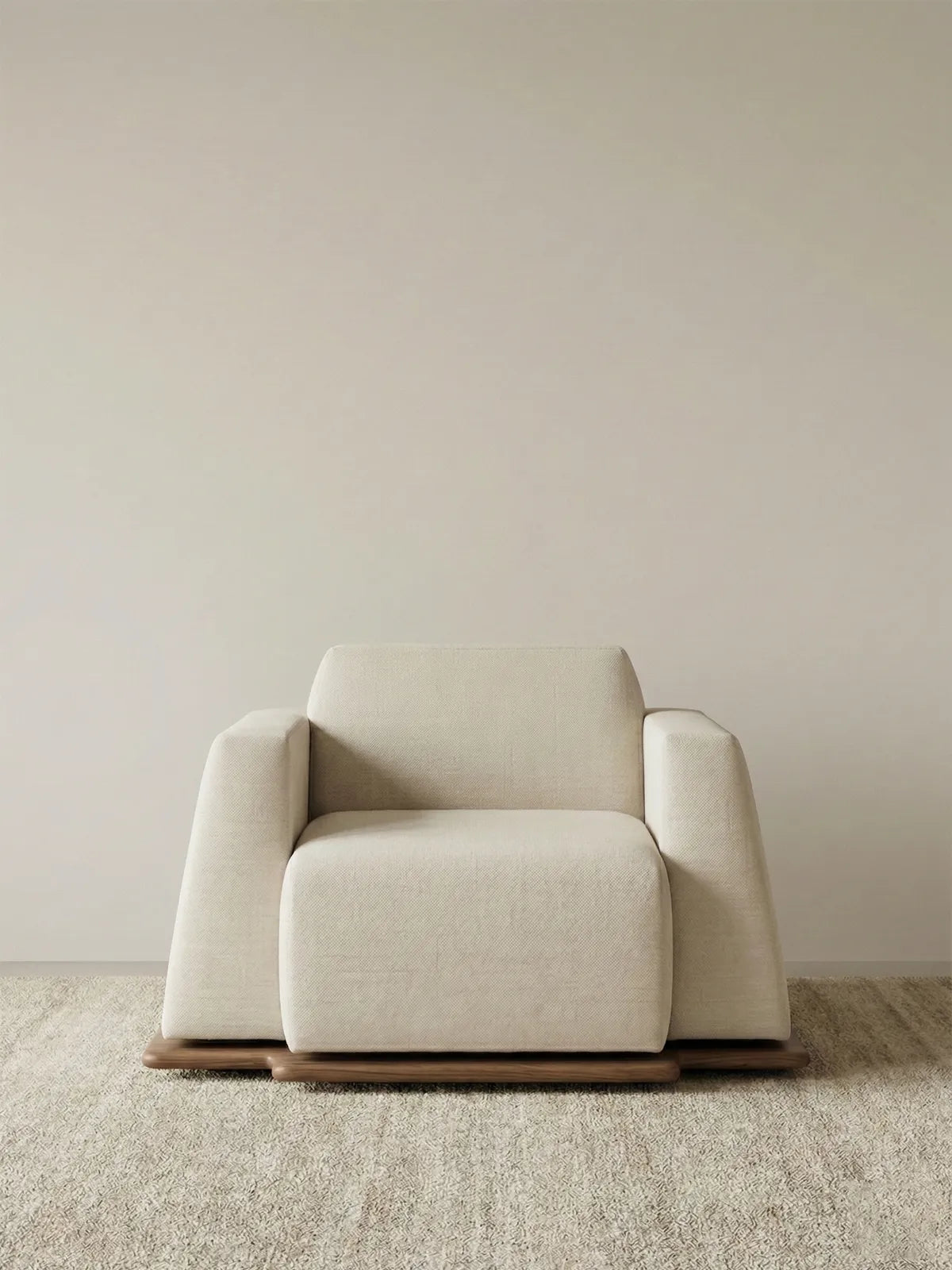 Studio front view of the Nara wide-seat lounge chair showing the low profile design and solid walnut plinth.