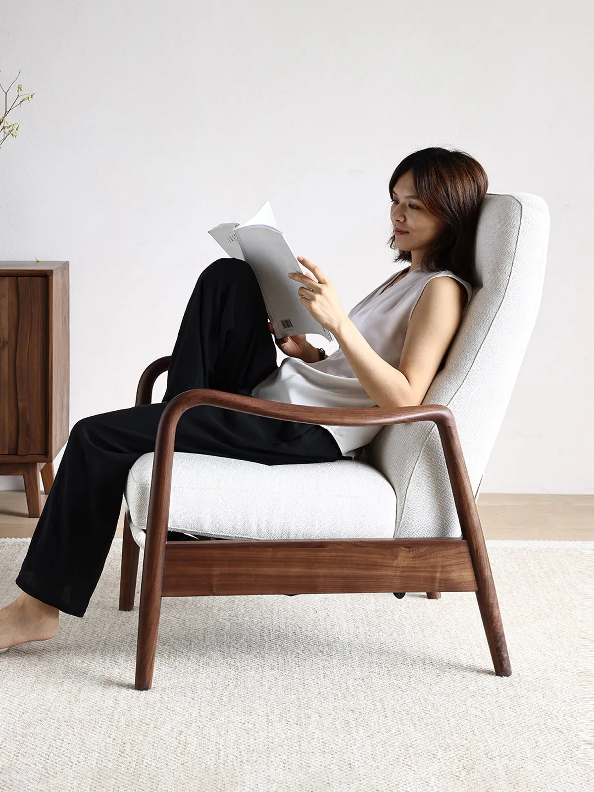 A woman relaxing and reading a book comfortably in The Haven Lounge Chair, highlighting its ergonomic back support and armrests.