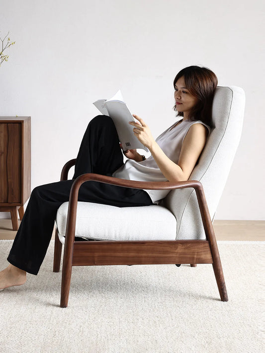 A woman relaxing and reading a book comfortably in The Haven Lounge Chair, highlighting its ergonomic back support and armrests.