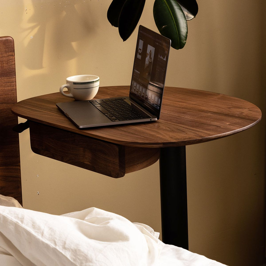 Adjustable walnut bed desk with laptop and coffee cup in cozy home workspace