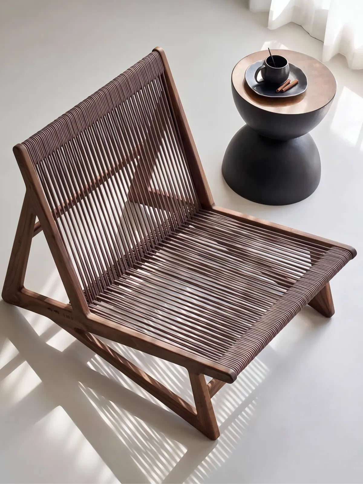 High-angle shot of woven rope wooden armchair next to a coffee table, showcasing the spacious seat design.